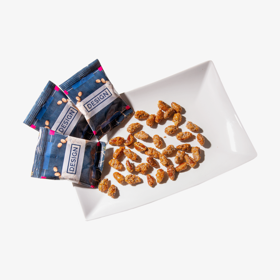 Gebrannte Mandeln in bedruckten Tütchen sowie lose Mandeln in einer weißen Schale