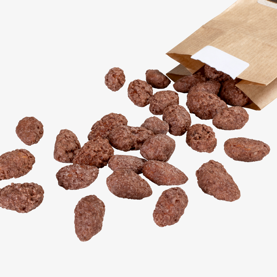 Gebrannte Confiserie-Mandeln, die aus einer Tüte aus Kraftpapier fallen