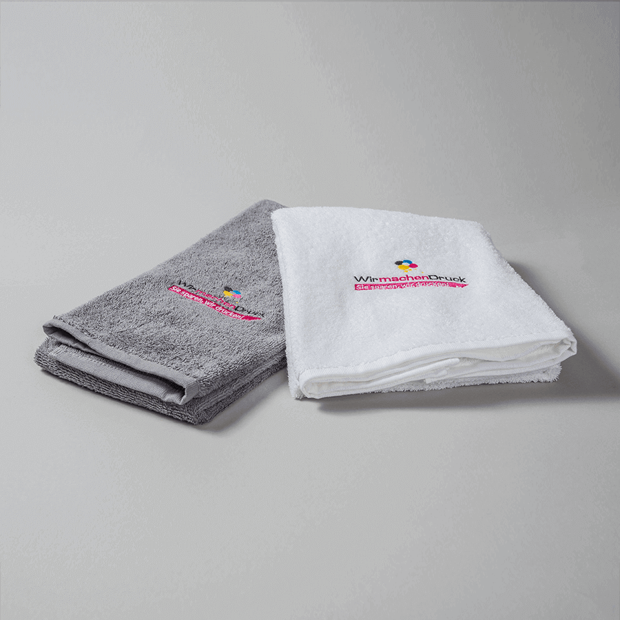 Ein graues und ein weißes Handtuch aus feinem Stoff mit individueller, mehrfarbiger Stickerei