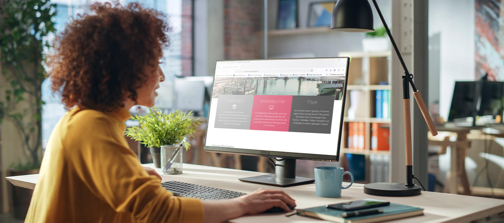 Lächelnde Person sitzt im Büro am Schreibtisch und guckt auf einen Bildschirm mit einem Resellershop